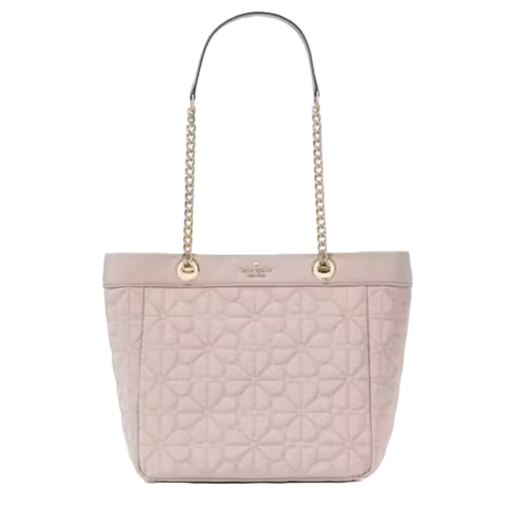 A quilted pink tote bag with chain and leather handles. The design features a subtle floral pattern, and the brand's logo is embossed near the top.