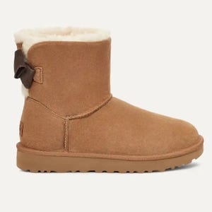 A pair of tan, suede ankle boots with fluffy interior lining and a side button detail.