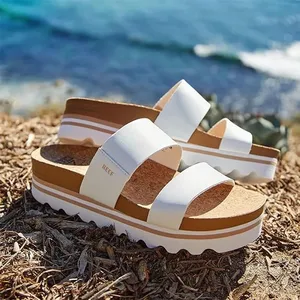 A pair of white strappy platform sandals by the sea.