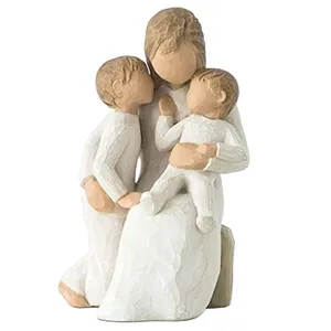 A sculpture depicting a faceless figurine of a seated woman holding a child on her lap, with another child standing nearby, all dressed in textured, white garments, representing a family scene.