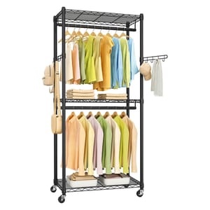 A black metal wheeled clothing rack with three shelves holds hanging clothes in pastel shades, folded towels, bags, a hat, and a scarf. Two garment rods offer additional hanging space, and side hooks provide extra storage options.