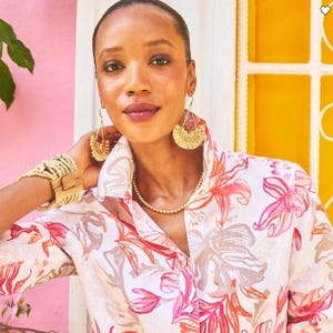 The No-Iron Tropical Floral Linen Shirt features a vibrant floral pattern in shades of pink and orange on a lightweight, wrinkle-free linen fabric. It's styled with a classic collar and long sleeves.