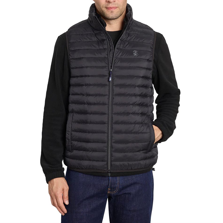 A man wears a black, quilted puffer vest over a black long-sleeve shirt and blue jeans. The vest features horizontal stitching and a small embroidered logo on the chest.