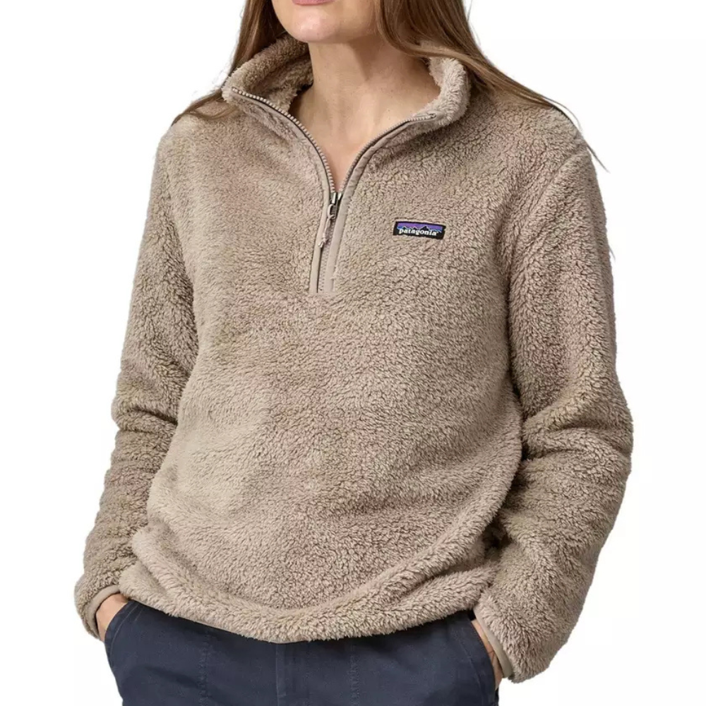 A person is wearing a taupe-colored, fuzzy Patagonia half-zip fleece pullover with their hands in their pockets.