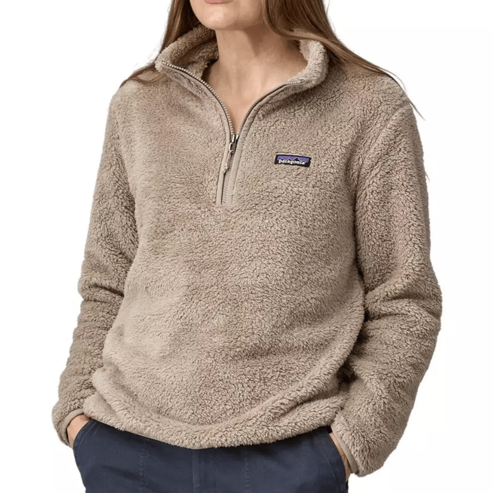 A person is wearing a taupe-colored, fuzzy Patagonia half-zip fleece pullover with their hands in their pockets.