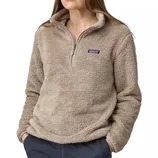 A person is wearing a taupe-colored, fuzzy Patagonia half-zip fleece pullover with their hands in their pockets.