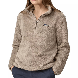 A person is wearing a taupe-colored, fuzzy Patagonia half-zip fleece pullover with their hands in their pockets.