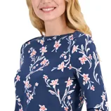 A woman wearing a navy blue top with a pink floral print, featuring long sleeves and a round neckline.