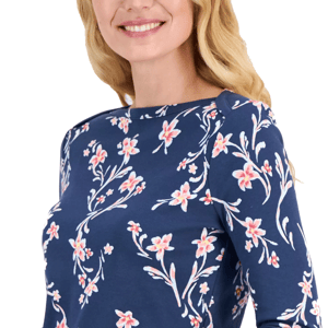 A woman wearing a navy blue top with a pink floral print, featuring long sleeves and a round neckline.