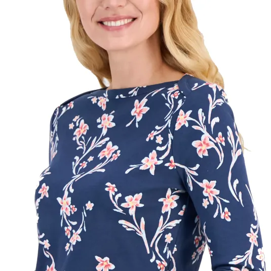 A woman wearing a navy blue top with a pink floral print, featuring long sleeves and a round neckline.