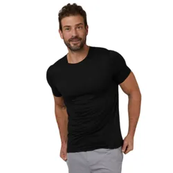 A man is wearing a black short-sleeve t-shirt and light gray shorts against a plain gray background.