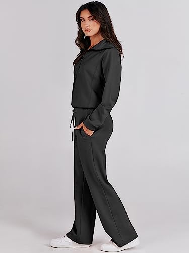 A woman is wearing a two-piece lounge set consisting of a long-sleeve hoodie with drawstring waist and wide-leg pants in a solid dark color, paired with white sneakers.