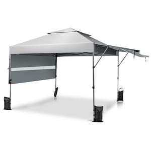 A gray pop-up canopy tent with a slanted roof and extended awning, featuring a sidewall and weighted bags at each leg for stability.