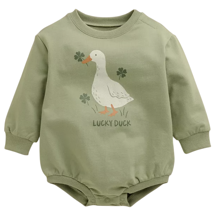 A green baby bodysuit features a duck and clovers illustration with the text \“Lucky Duck.\“ It has long sleeves and snap buttons at the bottom.