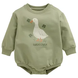 A green baby bodysuit features a duck and clovers illustration with the text \“Lucky Duck.\“ It has long sleeves and snap buttons at the bottom.