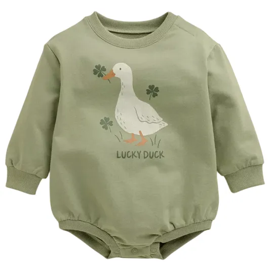 A green baby bodysuit features a duck and clovers illustration with the text \“Lucky Duck.\“ It has long sleeves and snap buttons at the bottom.