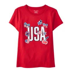 Red T-shirt with \“USA\“ printed in bold letters, surrounded by patriotic-themed icons like stars, butterflies, hearts, and cherries in red, white, and blue colors.