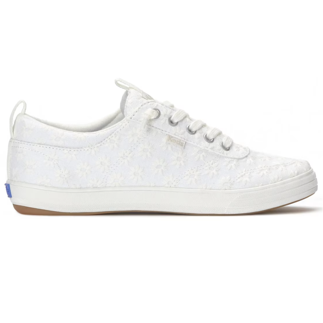 White low-top sneaker with floral lace overlay, featuring lace-up design and rubber sole.