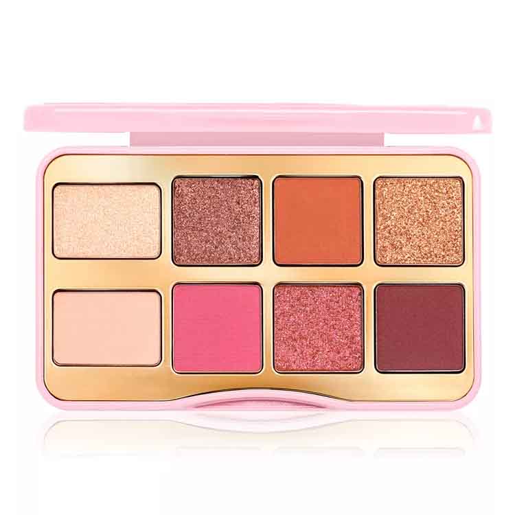 Too Faced Let's Play Mini Eye Palette features eight shades in a mix of matte and shimmer finishes, including warm tones like orange, pink, brown, and various sparkling hues, all housed in a compact pink case.