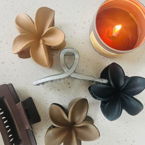 Hair clips shaped like flowers, a lit candle, and a hair comb.