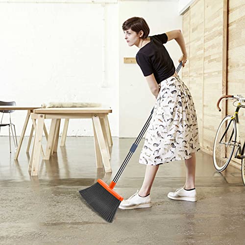 A person is using an extendable broom with a black bristle head and an orange dustpan on a long handle to sweep a concrete floor.