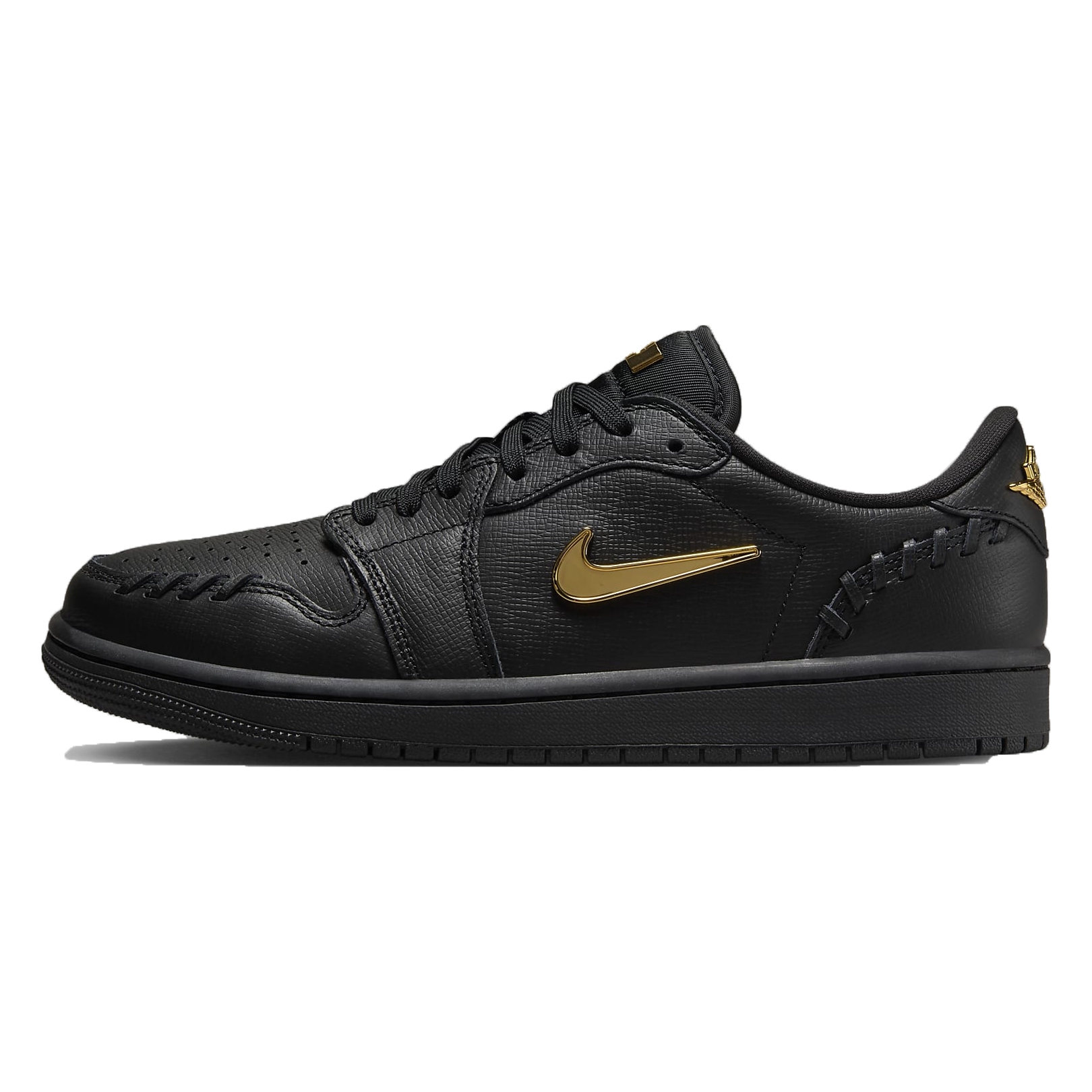 The Air Jordan Low Method shoes are all-black with a textured leather upper, featuring metallic gold accents on the Nike swoosh and branding. They have unique stitching details around the toe and heel for a stylish look.