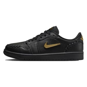 The Air Jordan Low Method shoes are all-black with a textured leather upper, featuring metallic gold accents on the Nike swoosh and branding. They have unique stitching details around the toe and heel for a stylish look.