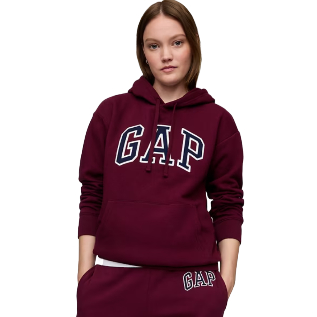 A person is wearing a maroon GAP hoodie with \“GAP\“ printed in large letters on the front, paired with matching maroon sweatpants, which also feature the GAP logo.