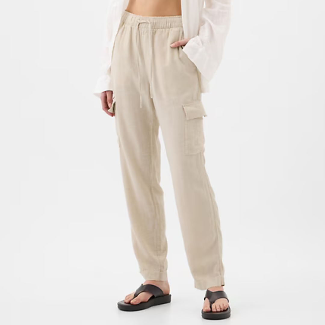 Light beige linen blend cargo pants with a drawstring waist, side pockets, and a flap pocket on the left leg, paired with black sandals.