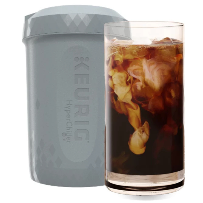 A Keurig HyperChiller next to a glass of iced coffee with cream swirling in it.