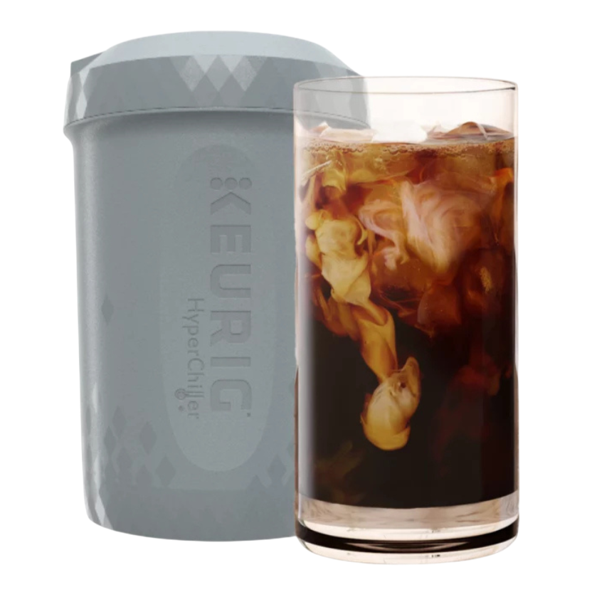 A Keurig HyperChiller next to a glass of iced coffee with cream swirling in it.