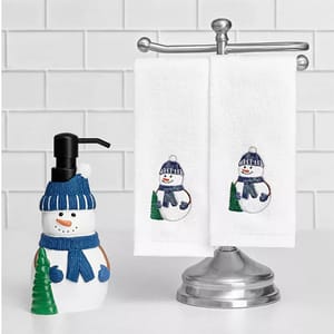 A snowman-shaped soap dispenser paired with two white hand towels, each embroidered with a snowman design, is displayed on a bathroom towel rack.