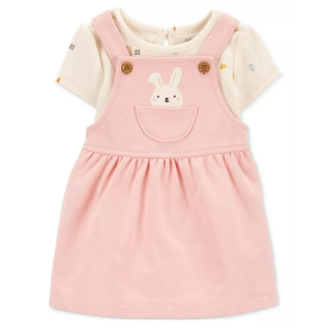 A cute 2-piece baby outfit featuring a light pink pinafore dress with a bunny design on the pocket, layered over a short-sleeve cream-colored shirt with subtle patterns.