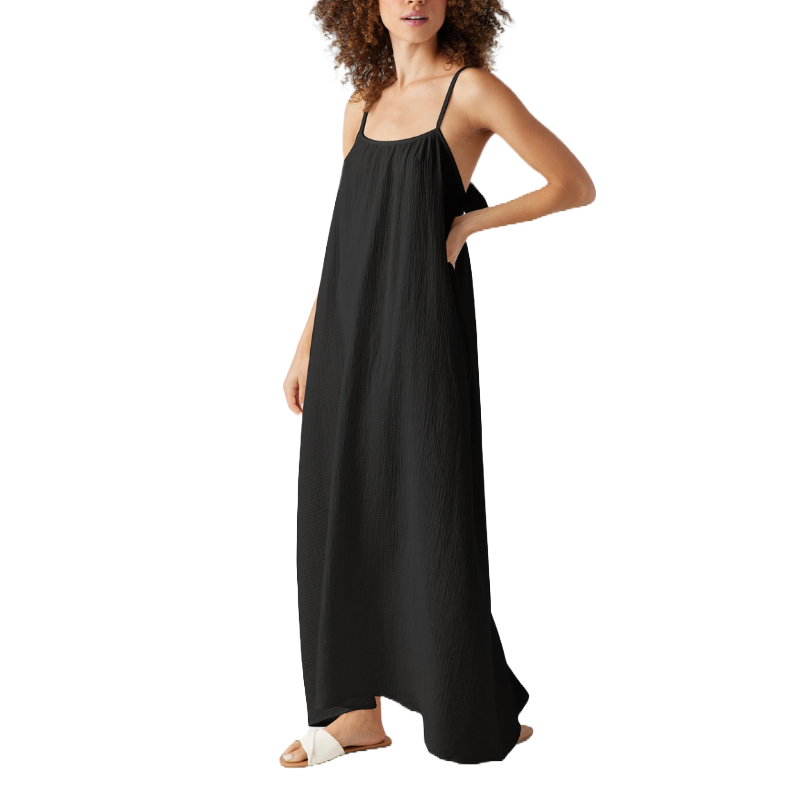 Sleeveless black gauzy maxi dress with thin straps, a loose fit, and ankle-length hem, paired with white slide sandals.
