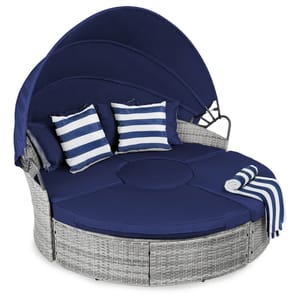 Blue canopy daybed with striped pillows and a side table, featuring a retractable sun cover.