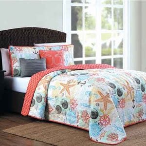 The 5pc Beach Queen Quilt Set features a coastal-themed quilt with starfish, seashells, and coral designs in light blue, orange, and white. It includes matching shams and decorative cushions.
