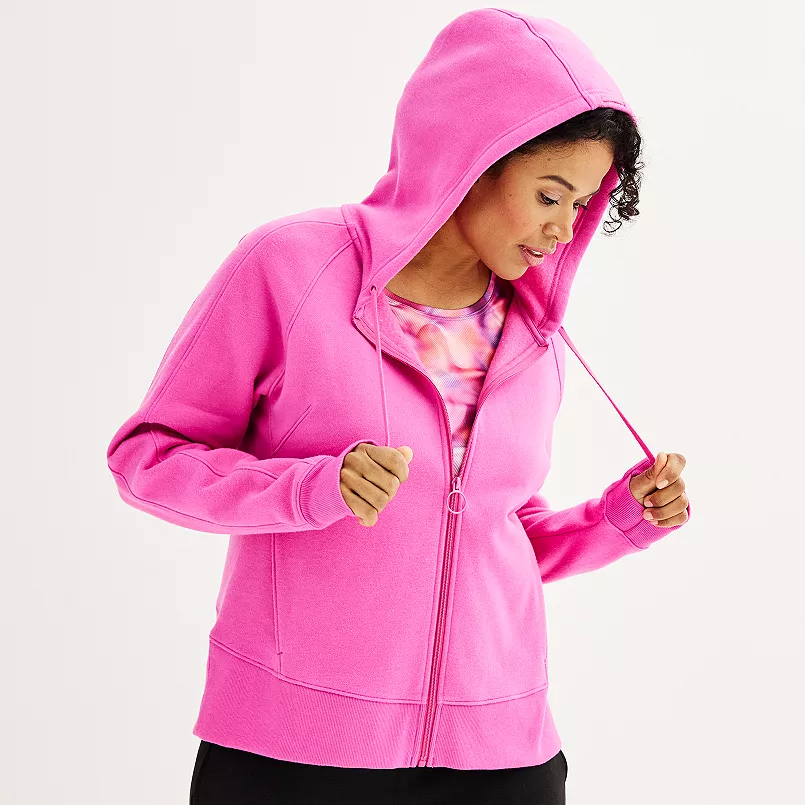 A woman wearing a bright pink zip-up hoodie with a hood and front pockets.