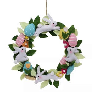 A decorative wreath featuring felt bunnies and colorful Easter eggs surrounded by green leaves and small flowers, arranged to create a festive, springtime design.