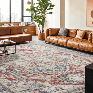A modern living room features a large patterned rug with blue, red, and beige tones, two brown leather sofas, a tall potted plant, and abstract wall art. A cityscape view is visible through large windows.