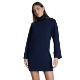 A woman is wearing a navy blue long-sleeve turtleneck dress with cuffed sleeves.