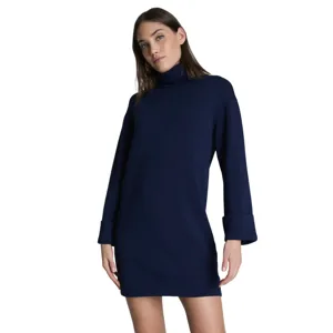 A woman is wearing a navy blue long-sleeve turtleneck dress with cuffed sleeves.
