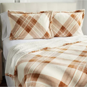 A bed set featuring a plaid patterned comforter and two matching pillow shams in shades of brown and cream, with a textured, soft appearance.
