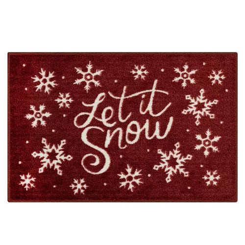A red doormat with white snowflakes and the phrase \“Let it Snow\“ in cursive font.