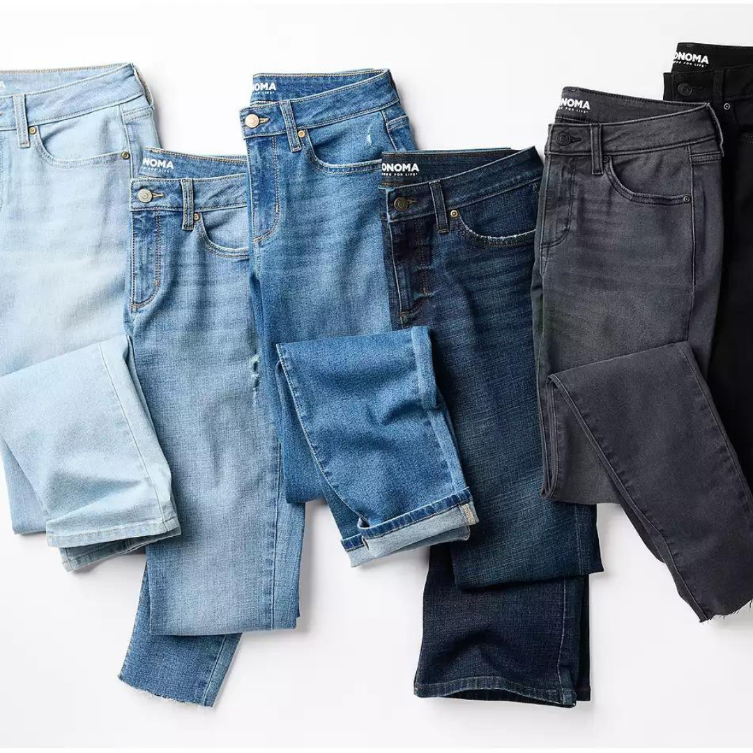 Five pairs of jeans in various shades of blue and gray, laid out flat and partially folded.