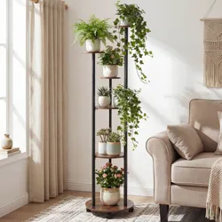 A vertical wooden and metal plant stand holds six potted plants, including ferns, ivy, and succulents, next to a beige sofa in a bright living room.