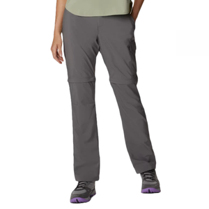 Columbia Women's Convertible Pants are dark gray, featuring a zip-off design allowing them to transform into shorts, making them versatile for hiking. They include pockets for convenience and are worn with active shoes.