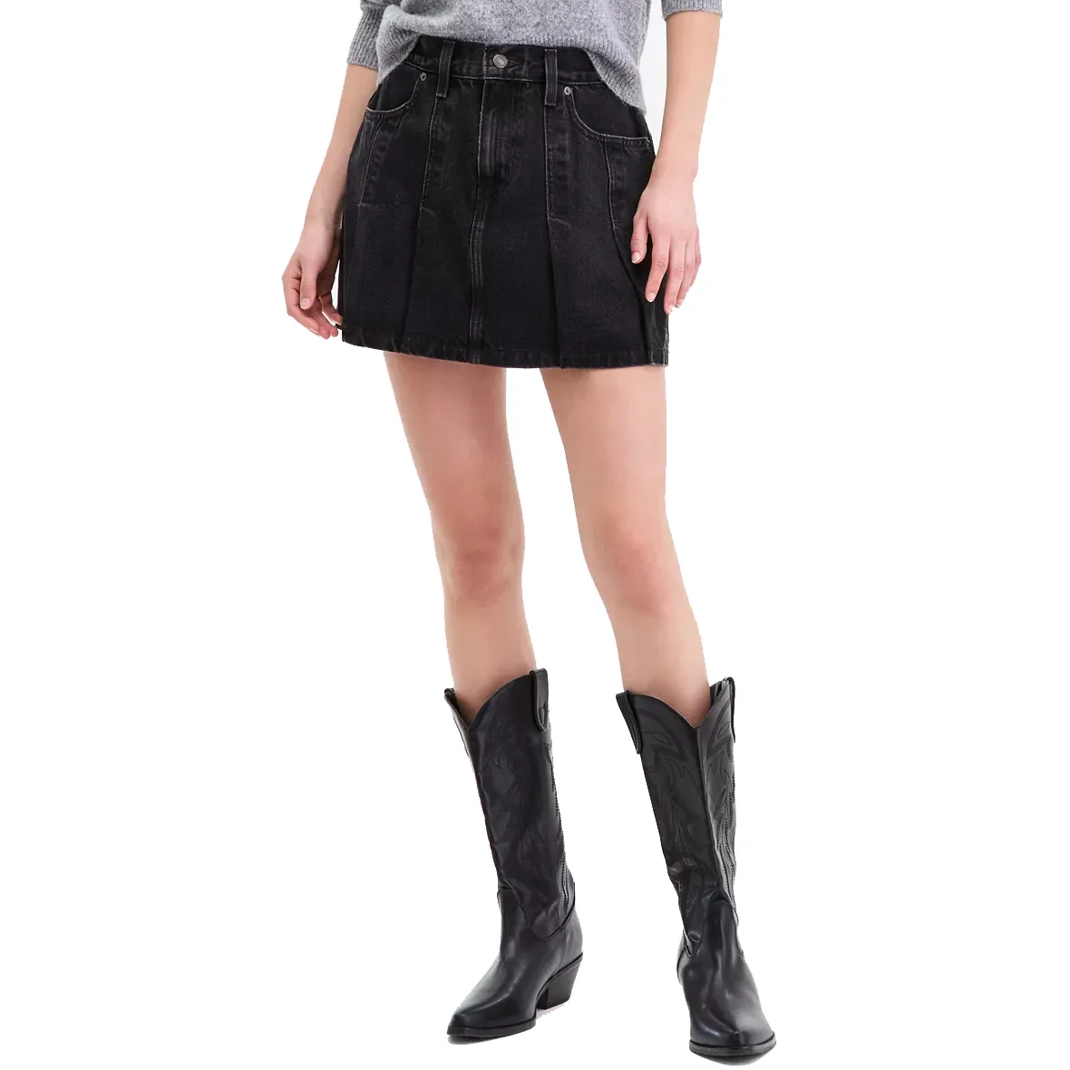 A woman's outfit featuring a gray sweater, black pleated denim mini skirt with front pockets, and black cowboy boots with decorative stitching.