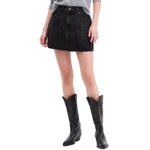 A woman's outfit featuring a gray sweater, black pleated denim mini skirt with front pockets, and black cowboy boots with decorative stitching.