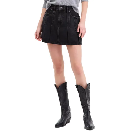 A woman's outfit featuring a gray sweater, black pleated denim mini skirt with front pockets, and black cowboy boots with decorative stitching.