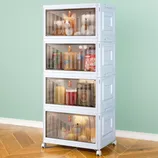 A stackable storage cabinet with transparent drawers houses beverages, canned drinks, and plush toys. The unit is on wheels and has a light blue design against a mint-green wall and wood-patterned floor.